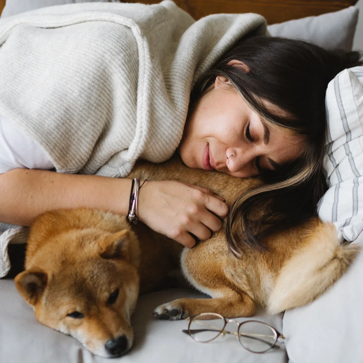 A woman napping on a sofa with her dog